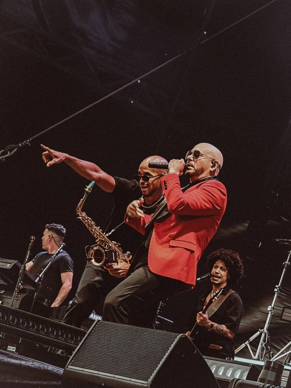 Pitbull sings and points to the audience while Luiso plays beside him, with the band behind.